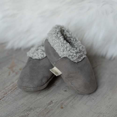 Baa Baby lambskin baby booties next to a white long hair sheepskin rug