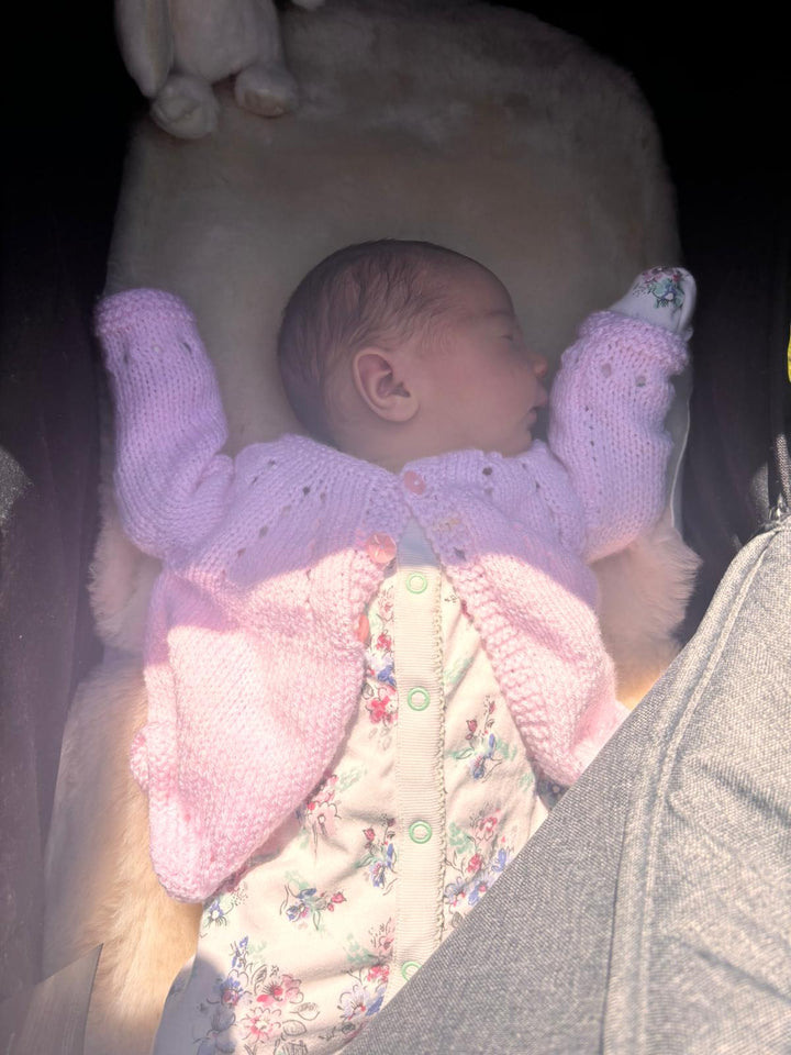 Newborn baby sleeping on a milk sheepskin pram liner