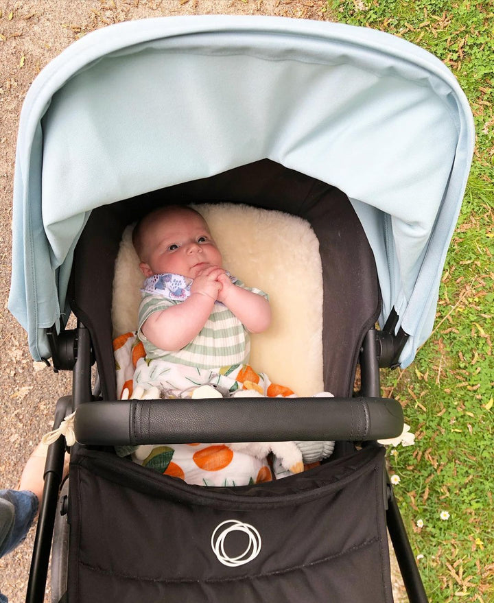 sheepskin pram liner in the bassinet section of the bugaboo fox with baby enjoying the ride, happy and cosy