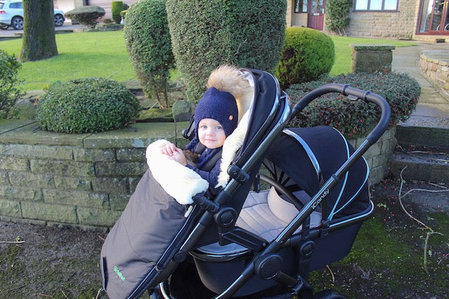 Sheepskin pram footmuff featured in a double pram icandy Peach with baby in front seat looking warm cosy and happy