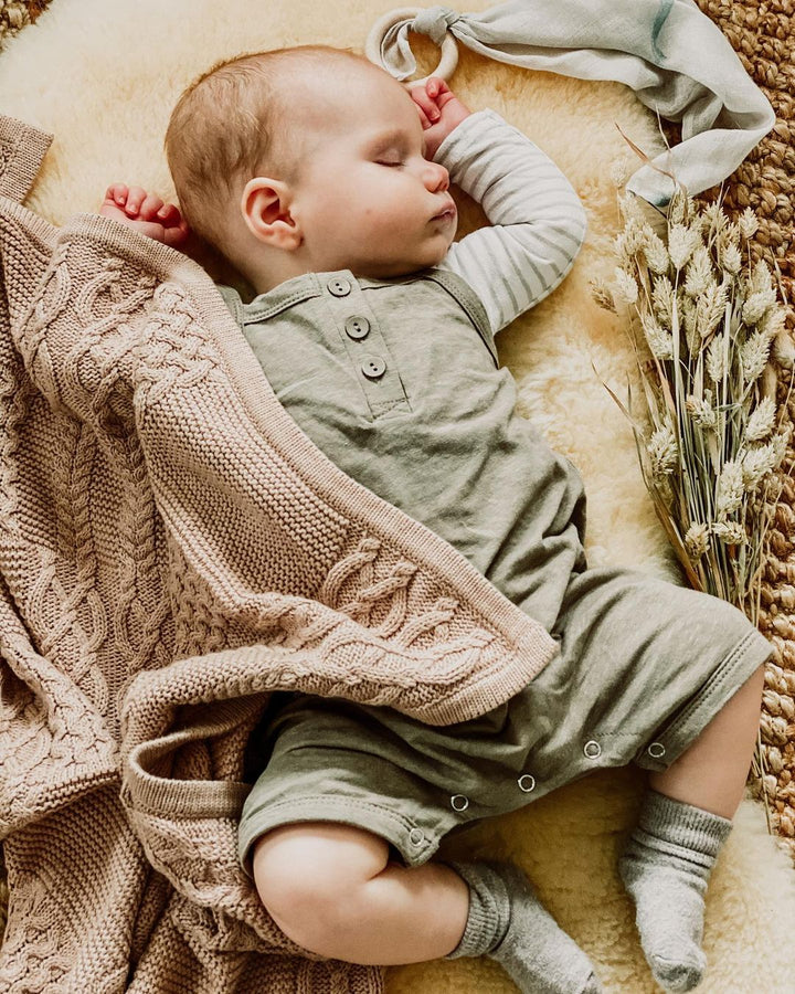 Baby asleep on a neutral sheepskin pram liner