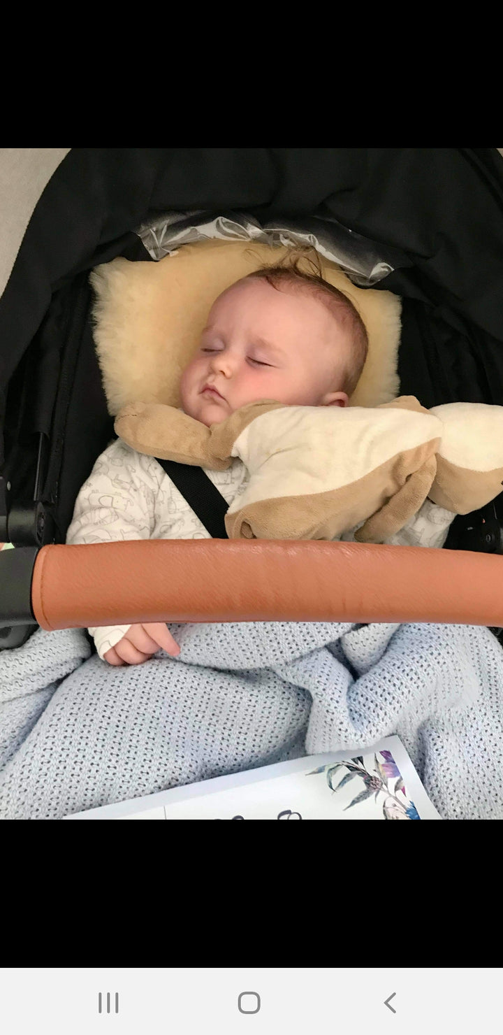 Baby sleeping on a honey sheepskin pram liner, settled and happy, pale milk shade , luxurious, natural and temperature regulating
