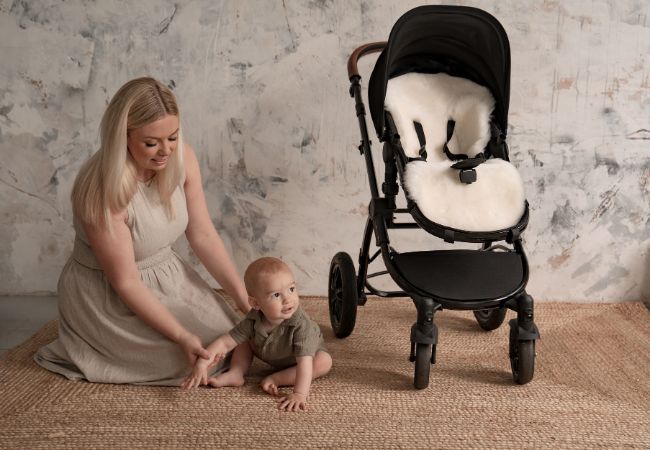Sheepskin milk pram liner in an Ickle Bubba pram with a baby sat beside