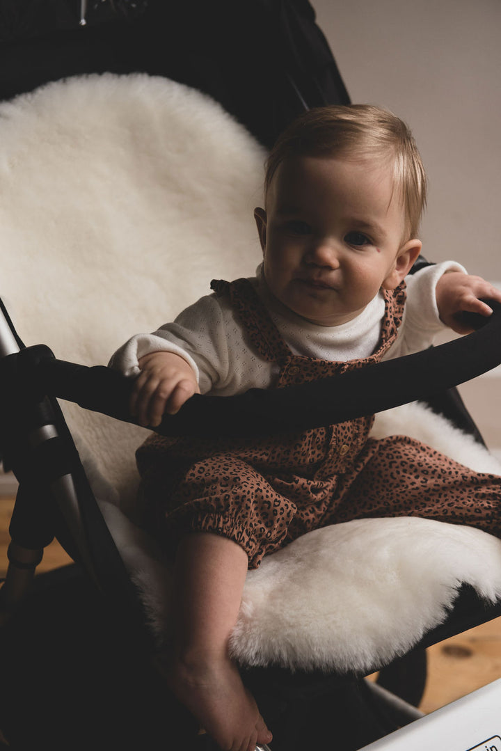 milk and honey sheepskin pram liner in an icandy pram with a toddler comfortable in the buggy seat