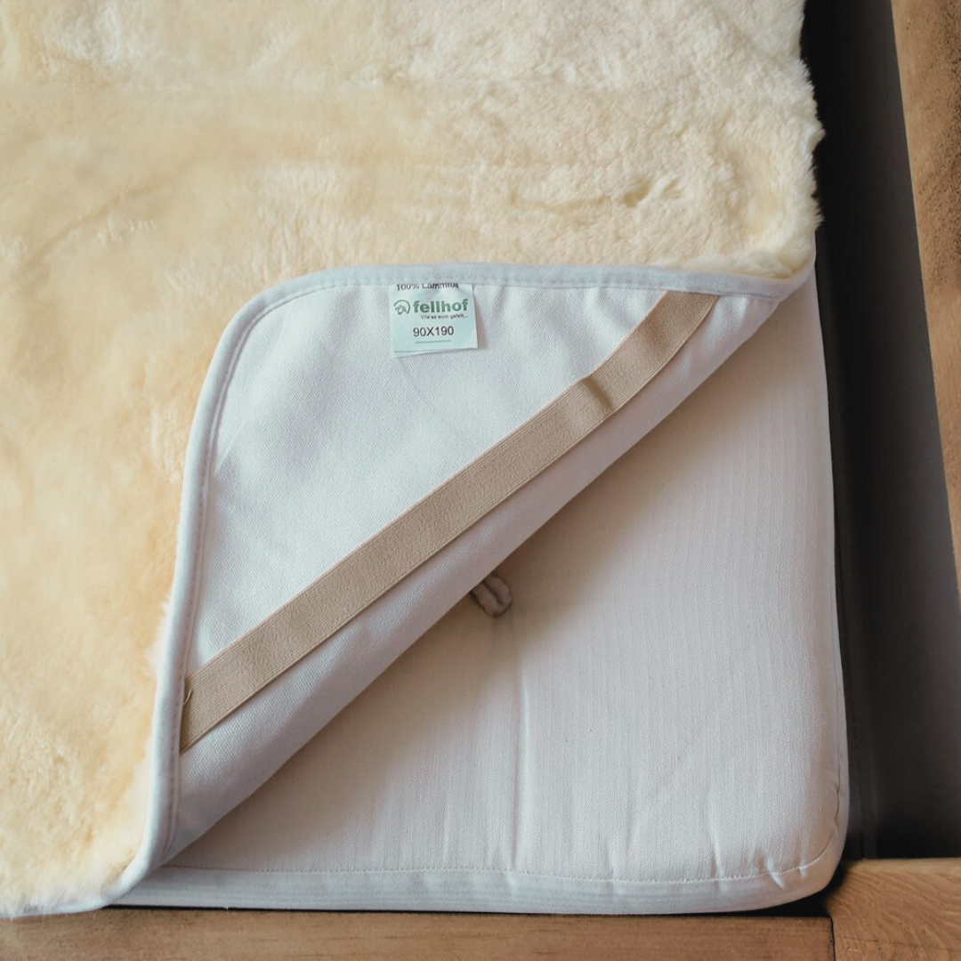 Sheepskin cot bed liner for a baby or toddler to help them sleep, showing how this Fellhof medical sheepskin attaches to the bed