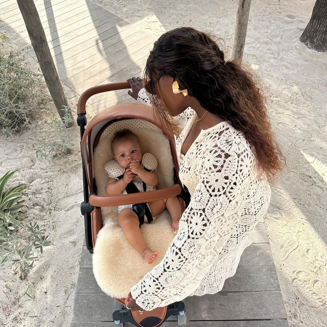 sheepskin pram liner with baby on the beach in the sun