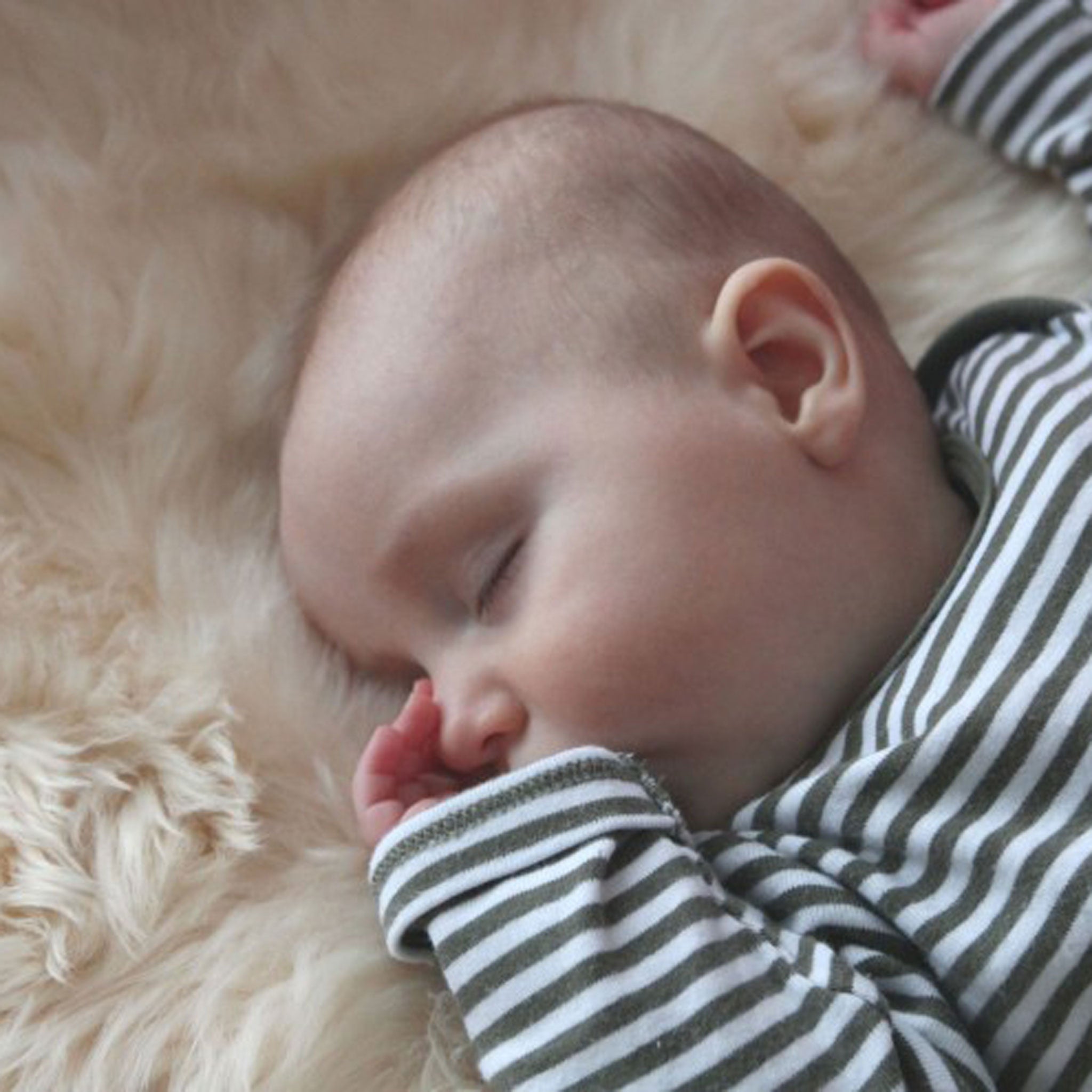 Baby sleeping on a natural sheepskin rug safe for baby