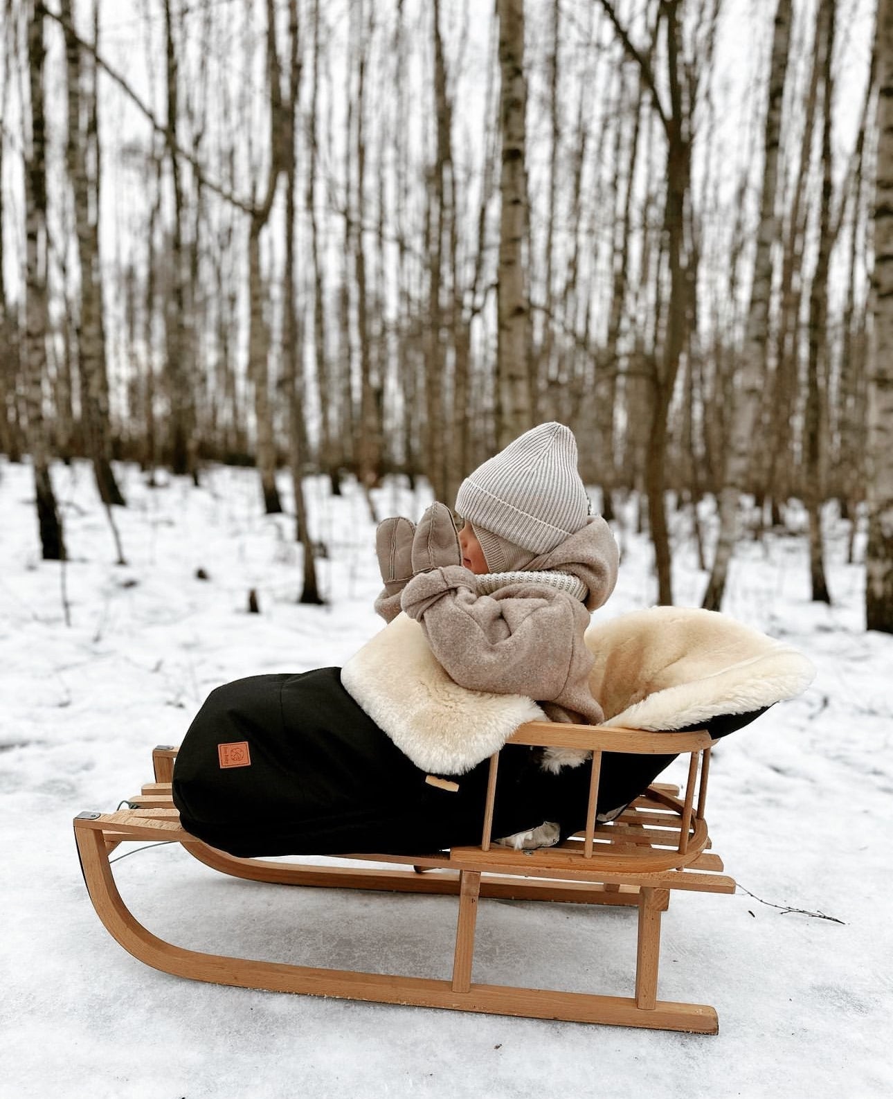 Sheepskin Pram Footmuff shown keeping a baby warm in the winter on a very cold day