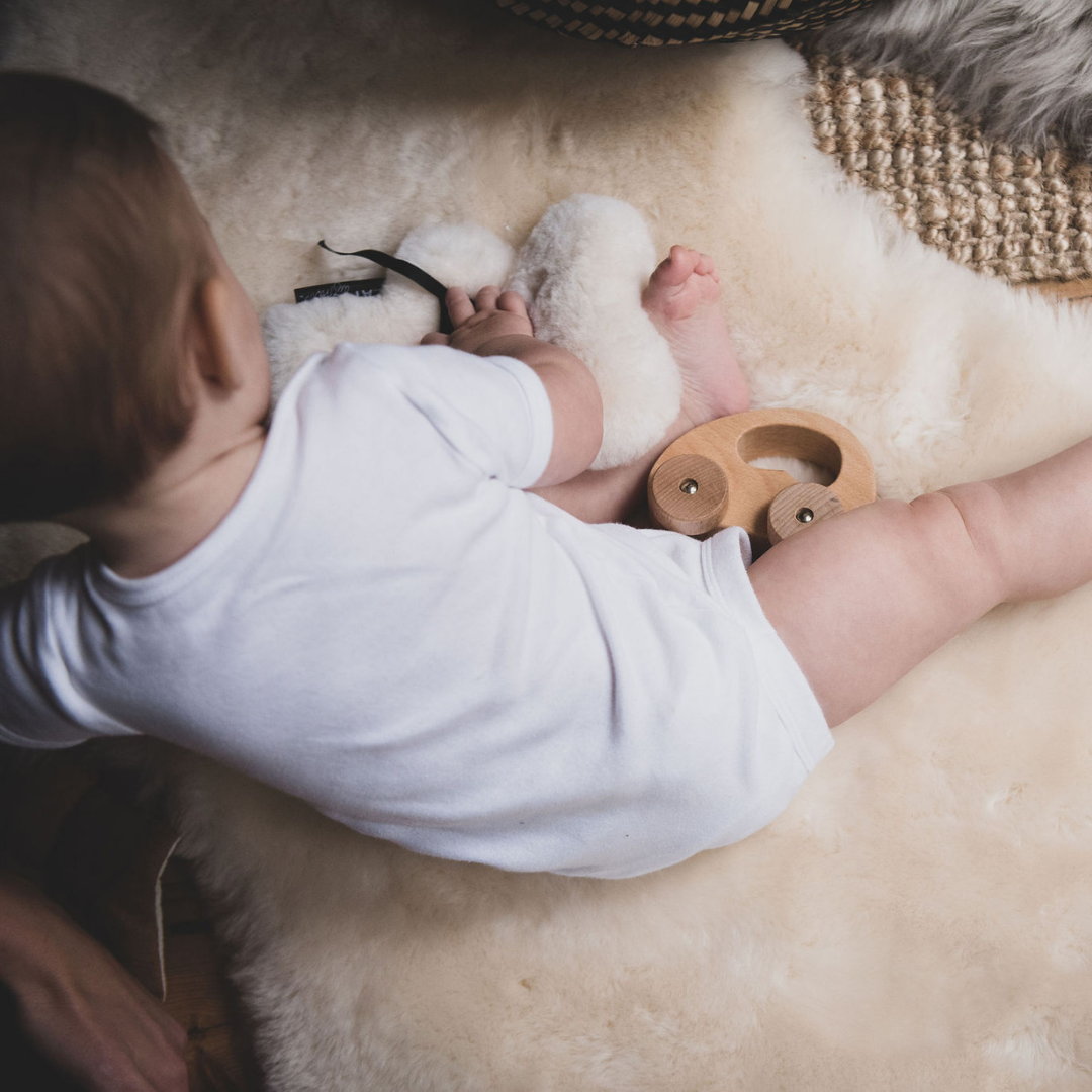 baby on sheepskin rug with baby toys