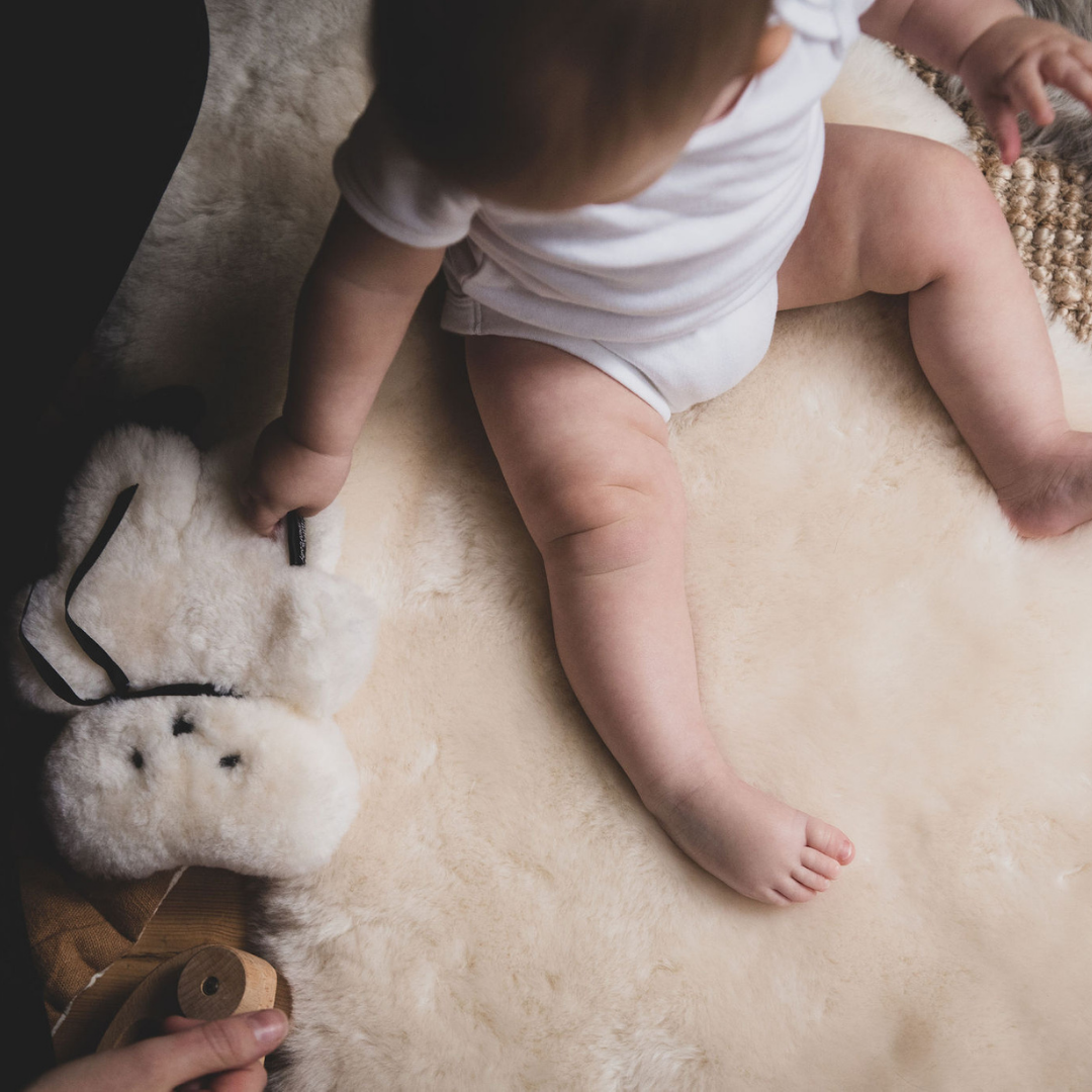 baby on sheepskin rug with FLATOUT bear