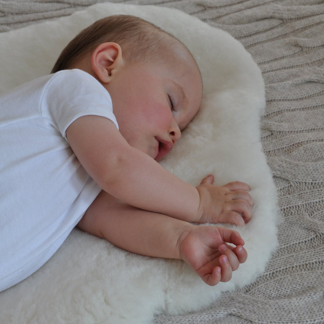 Baby asleep on a white baby-safe medical sheepskin nursery  rug