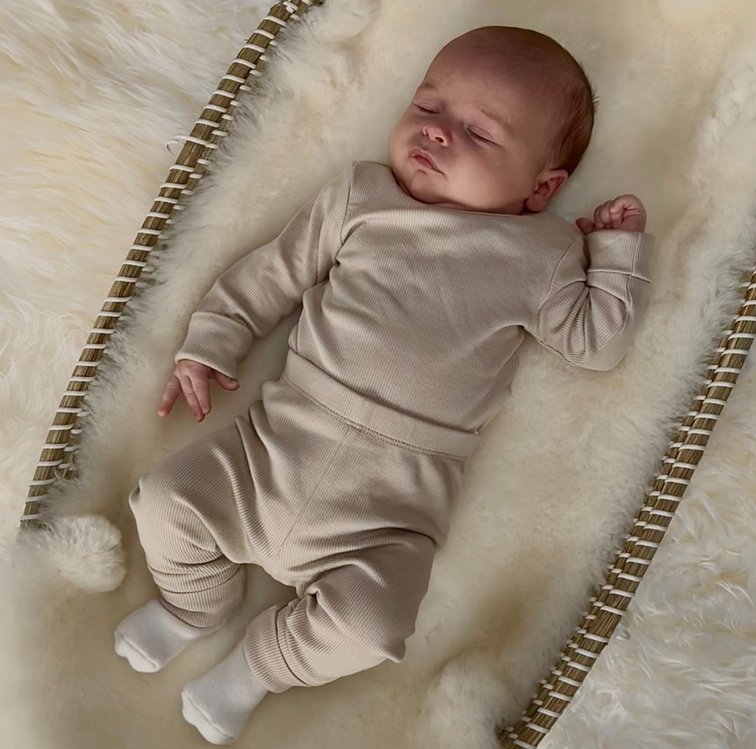 Newborn baby asleep on back on sheepskin to help soothe and comfort and support