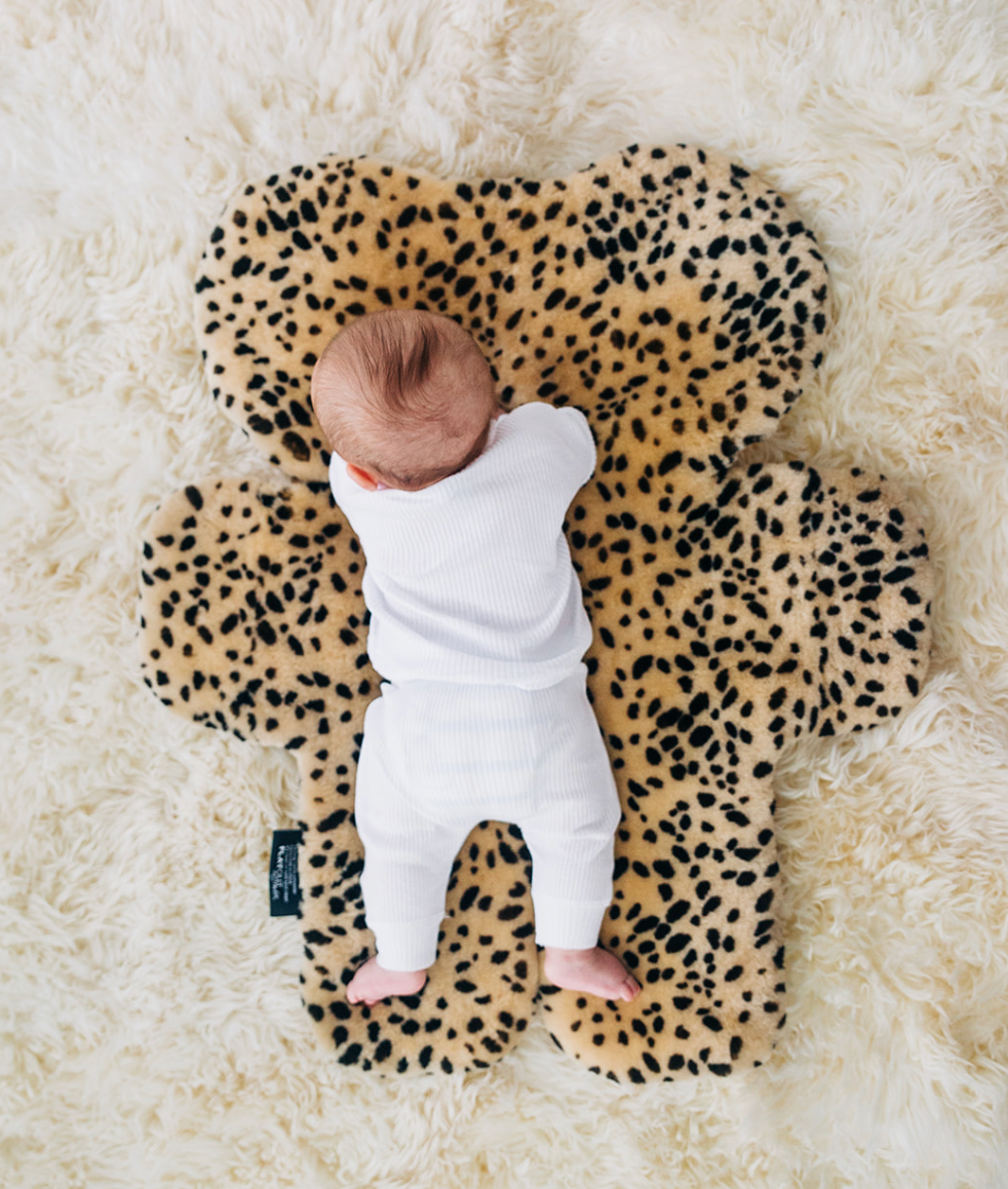 Sheepskin rug with leopard print and baby laying on it for tummy time