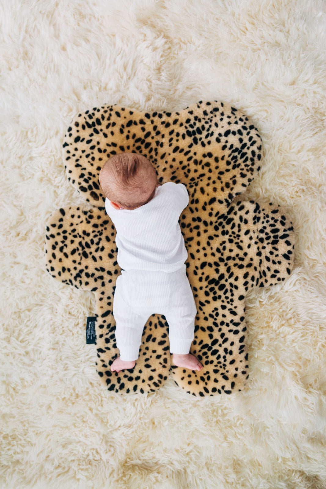 Leopard print sheepskin nursery rug with baby laying on top for tummy time and playtime