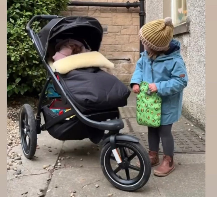 Black pram footmuff for Thule with full sheepskin lining and baby sleeping and cosy in the cold weather