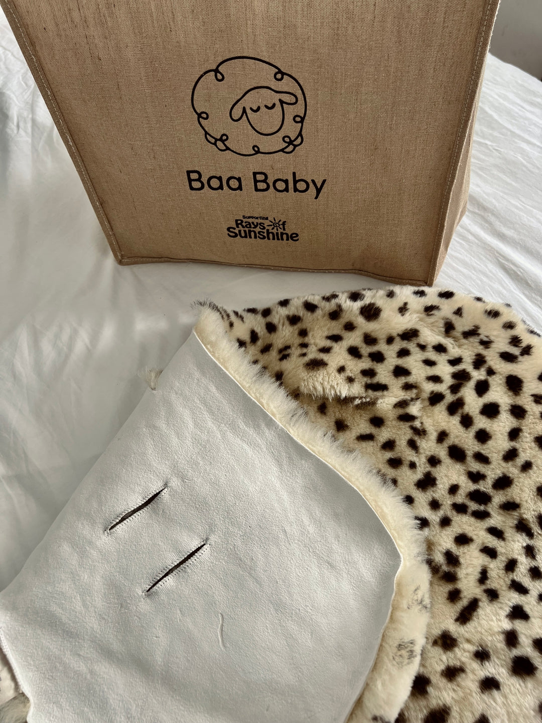 Sheepskin buggy liner with leopard print, vertical harness openings to fit a cybex