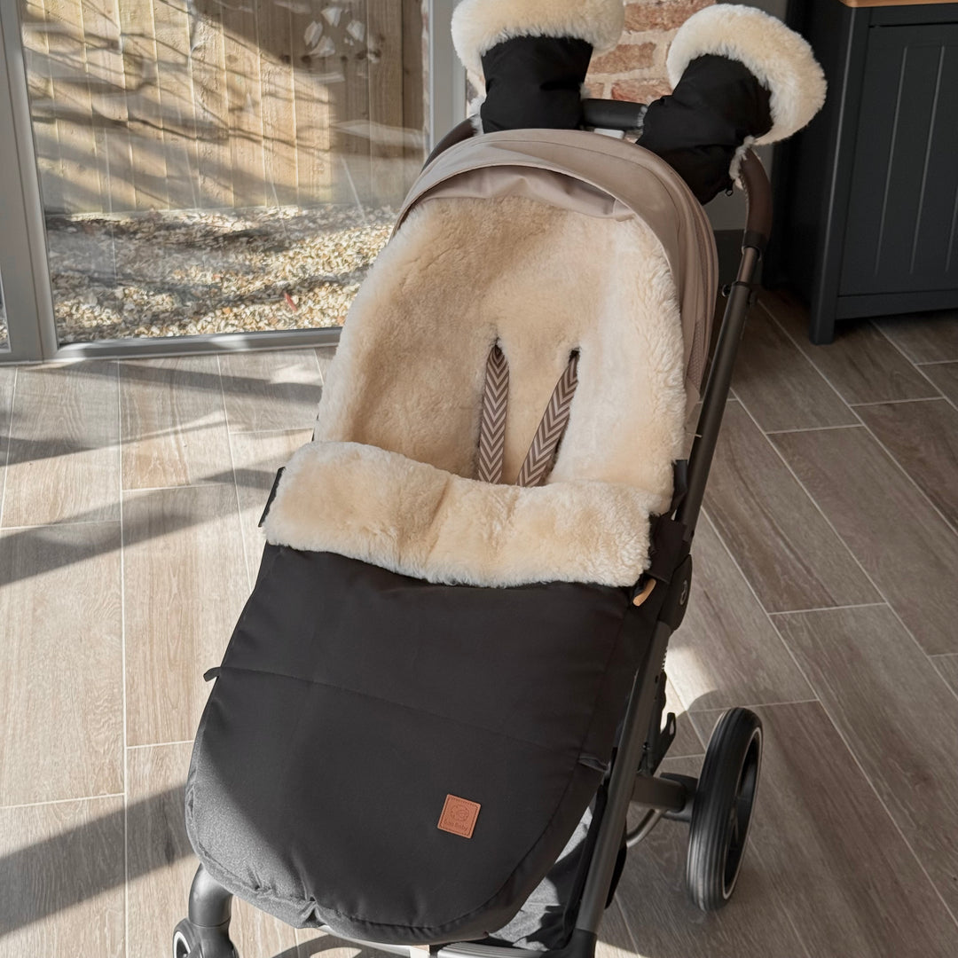 Cybex Pram with a sheepskin footmuff perfectly fitting, shown in black with milk lambskin and matching pram handwarmers