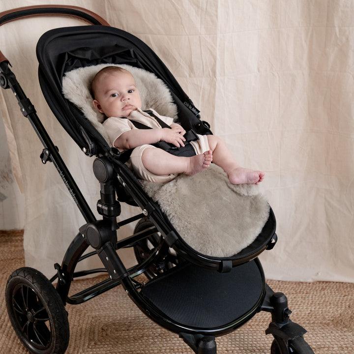 Pale Brown Natural Shorn Lambskin Bugaboo™ Pram Liner for Comfort and Sleep, baby laid in a pram lined with neutral sheepskin