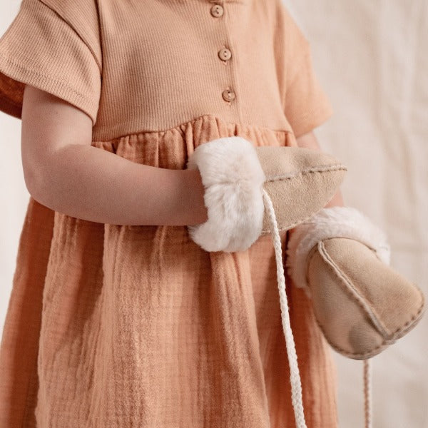 A little girl wearing neutral mittens on string