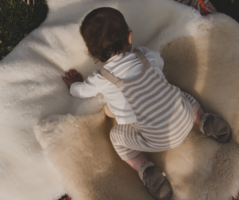 Baby playing on sheepskin rugs outdoors, white ,milk and honey sheepskin rugs