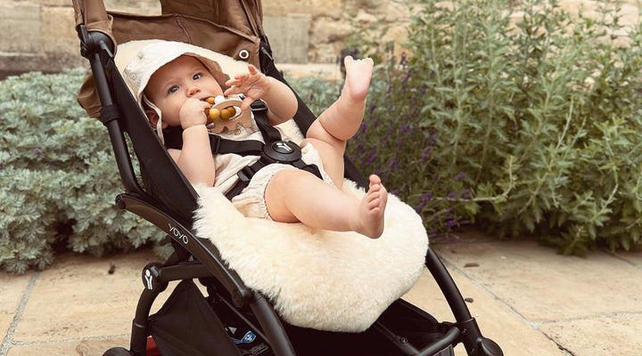 Baby in a yoyo pram  with a sheepskin liner, happy and smiling and keeping him cool