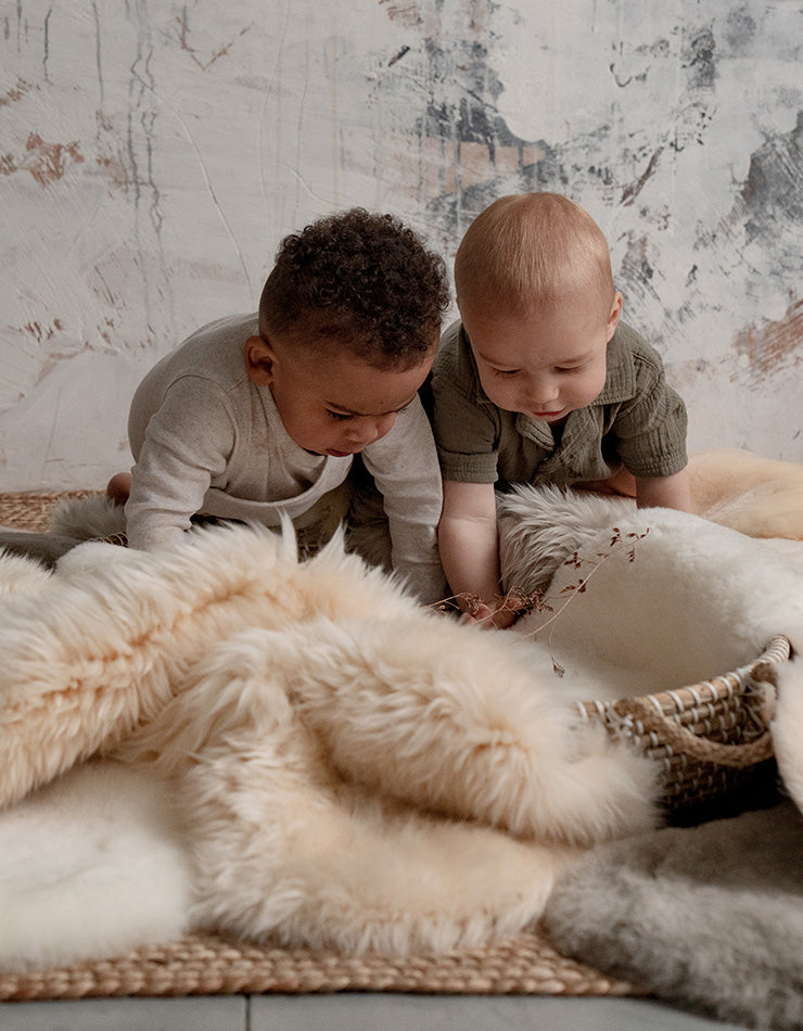 Sheepskin rugs baby safe for a nursery with two babies playing on there along with a bassinet 