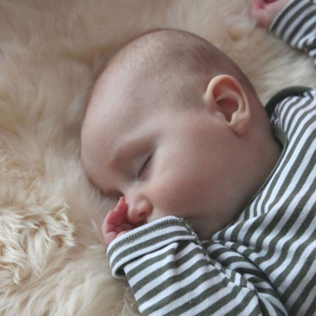 Baby Sleeping on cooling Sheepskin in a pram
