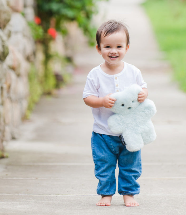 Toddler boy holding loved teddy bear made of sheepskin in baby blue from FLATOUT Australia,  genuine merino