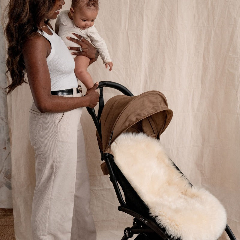 Mum and baby with a babyzen yo-yo pram which has a neutral coloured sheepskin liner in it, perfect for cooling babies down in the summer