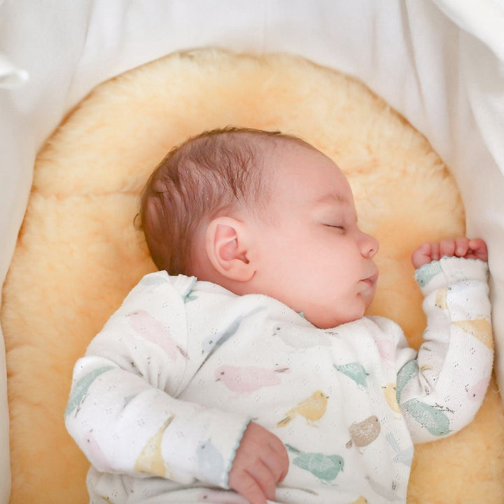 Baby Sleeping Peacefully on Lambskin Moses Basket Liner for Comfort and Temperature Regulation
